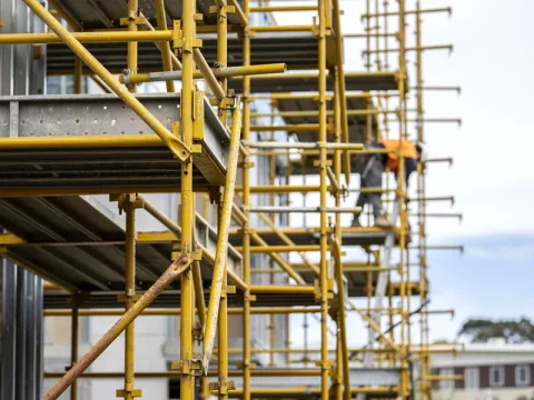 Kwikstage scaffolding system set up on a commercial construction site with a worker in a high-vis jacket.