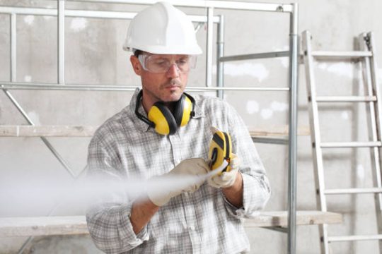 Construction worker inspecting equipment near kwikstage scaffolding on site