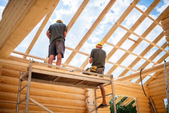 Construction workers standing on scaffolding during timber roof framing work