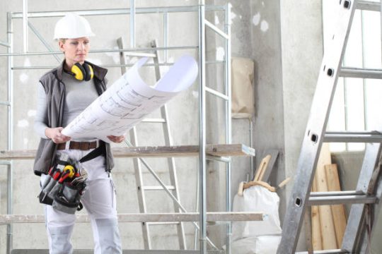 female builder reviewing plans beside kwikstage scaffolding