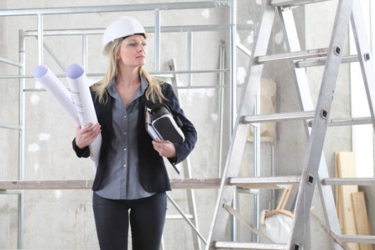 construction professional holding plans near timber plank and kwikstage scaffolding structure