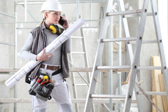 construction worker with plans near kwikstage scaffolding and timber plank access equipment