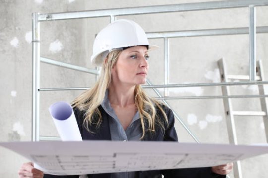 Site supervisor reviewing plans beside mobile scaffolding during construction work
