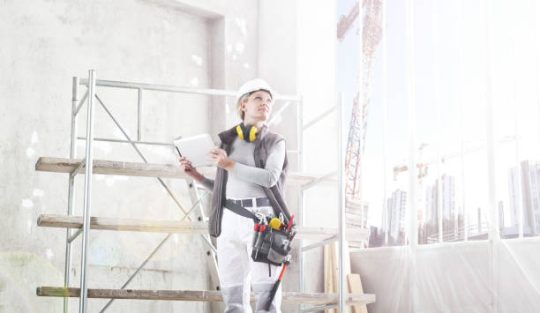 Tradesman working beside mobile scaffold during building renovation project